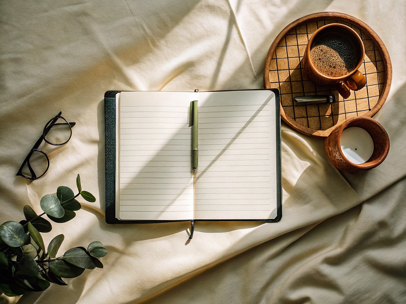 An open ledger, a pen, and a cup of coffee in warm daylight